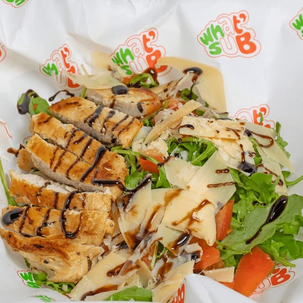 Grilled chicken salad with arugula, tomatoes, parmesan, and balsamic glaze in a What's Sub wrapper.